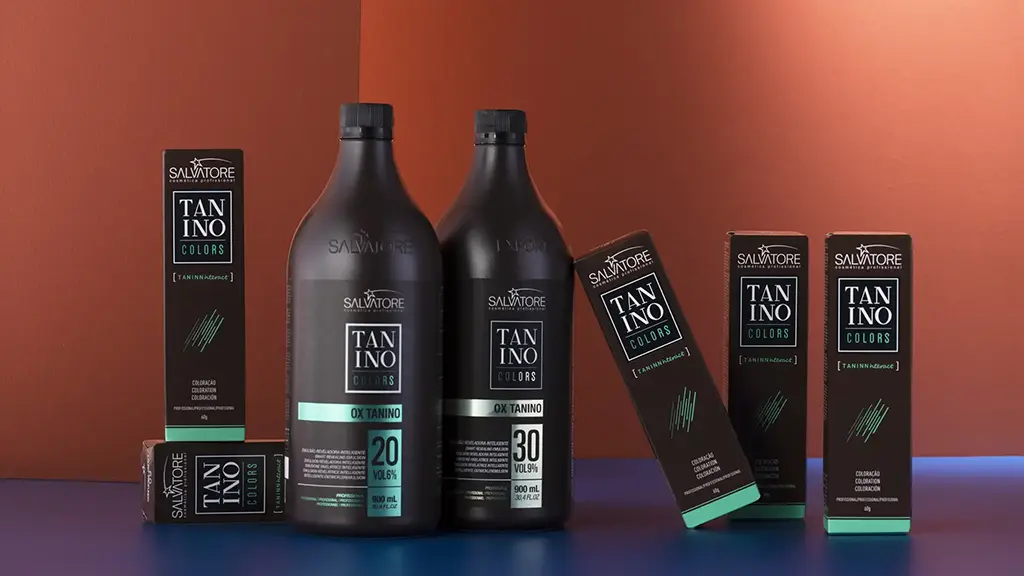 kit para coloração composto pelos produtos : Tubos de coloração Salvatore; OX Tanino apoiados em uma base de azul e com um fundo liso laranja com passagem de luz.